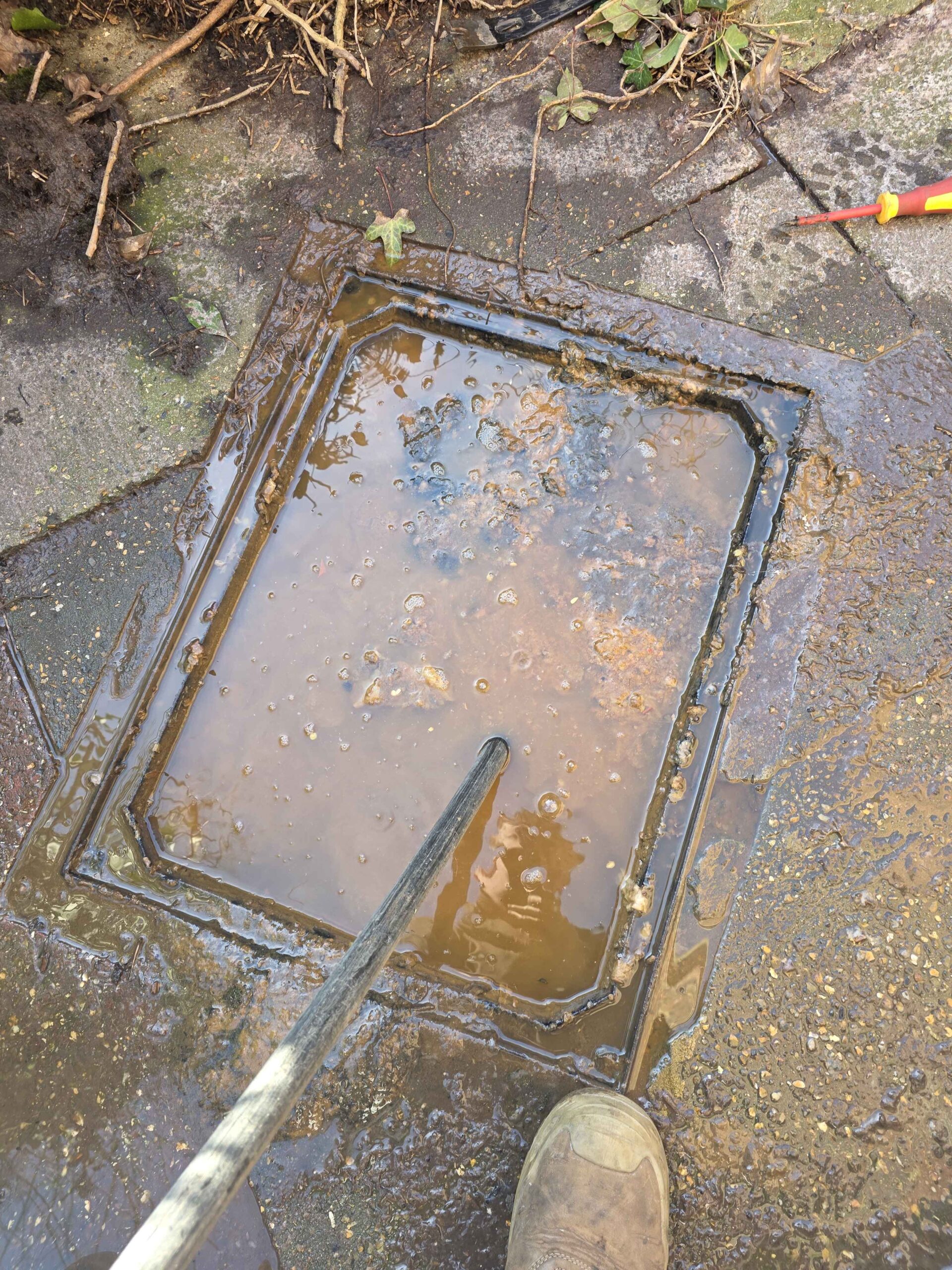 Flooded manhole cover being lifted for drain clearance